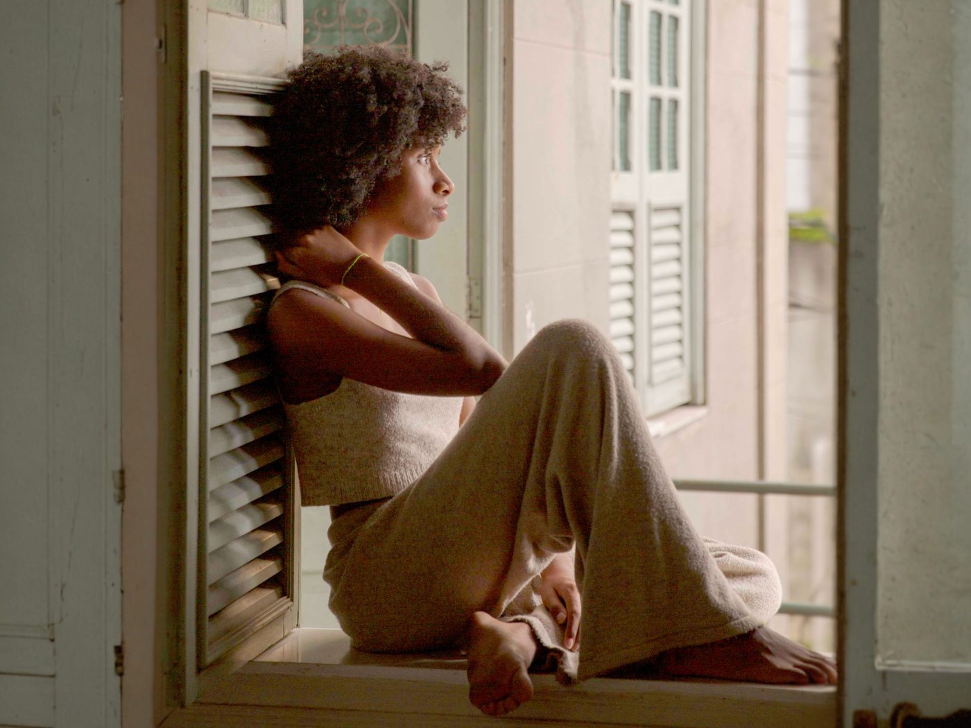 Person sitting on a wide windowsill in soft daylight, looking out